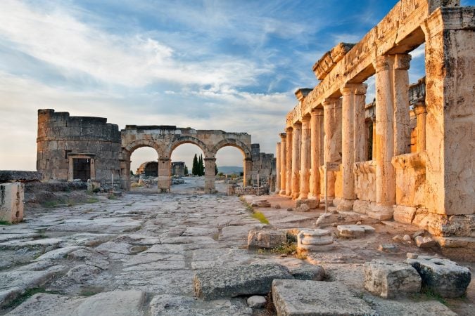 Ancient ruins and columns of Hierapolis bathed in golden light.