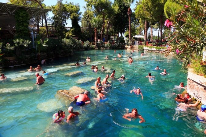 Tourists relaxing in the hot spring pools among ancient ruins.