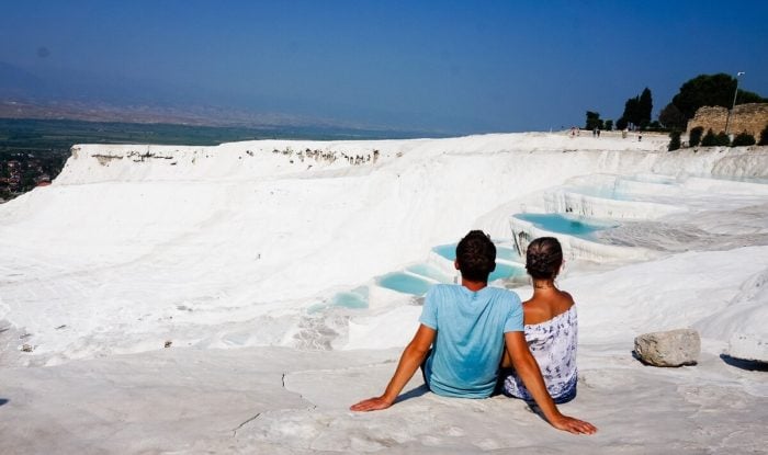 A couple sitting on the white travertine terraces, peacefully watching the stunning Pamukkale landscape.
