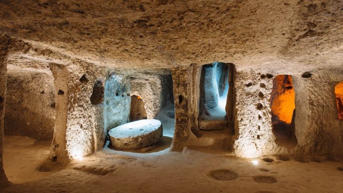 Underground room with a round stone door and carved niches in Derinkuyu Underground City, Cappadocia.