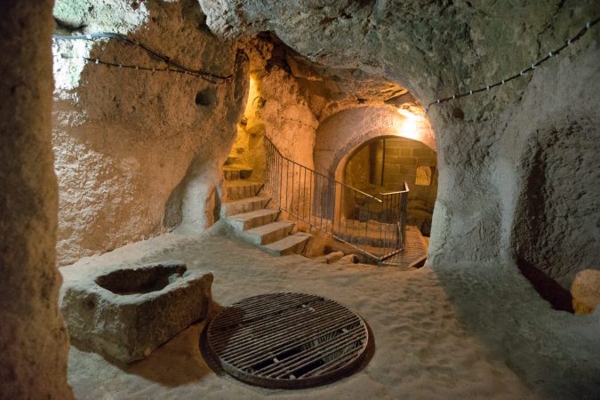 Rock-cut tunnels and connected chambers with warm lighting inside Kaymakli Underground City, Turkey.
