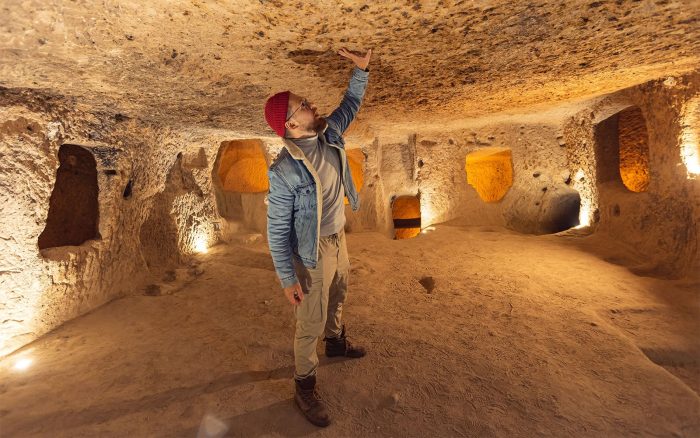 Visitor walking through a carved tunnel and rooms inside Kaymakli Underground City in Cappadocia.