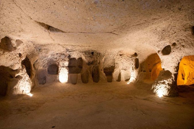Wide carved chamber with wall niches and warm lighting inside Kaymakli Underground City, Cappadocia.