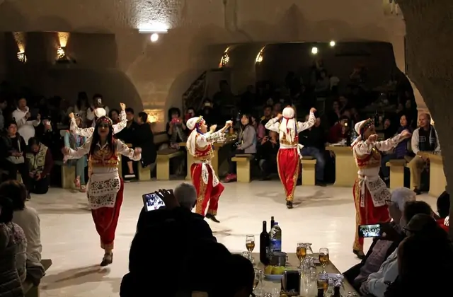 Un derviche giróvago girando con una túnica blanca durante la ceremonia espiritual Sema en el espectáculo de noche turca de Capadocia, enmarcado por los paisajes monumentales de la región. La hipnótica actuación del derviche giróvago es una de las tradiciones culturales más icónicas de Turquía y el