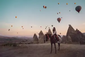 Tres caballos pastando en Capadocia junto a viviendas rupestres y chimeneas de hadas