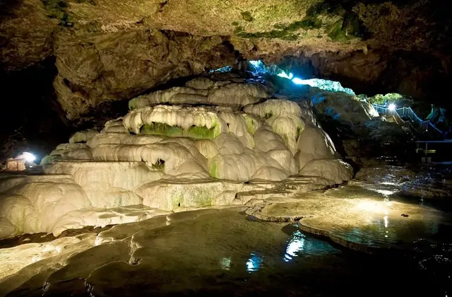Piscina subterránea dentro de la cueva de Kaklik en Denizli, Turquía, reflejando las paredes de la cueva y formaciones de travertino con poca luz