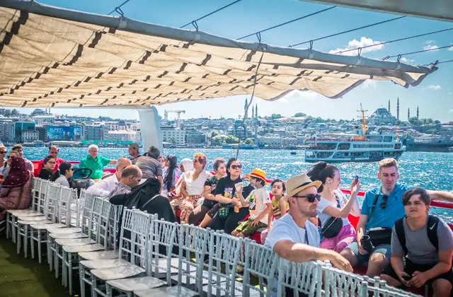 I passeggeri si godono l'aria fresca sul ponte aperto di una crociera sul Bosforo a Istanbul, ammirando ampie vedute dello stretto durante un memorabile viaggio panoramico tra due continenti.