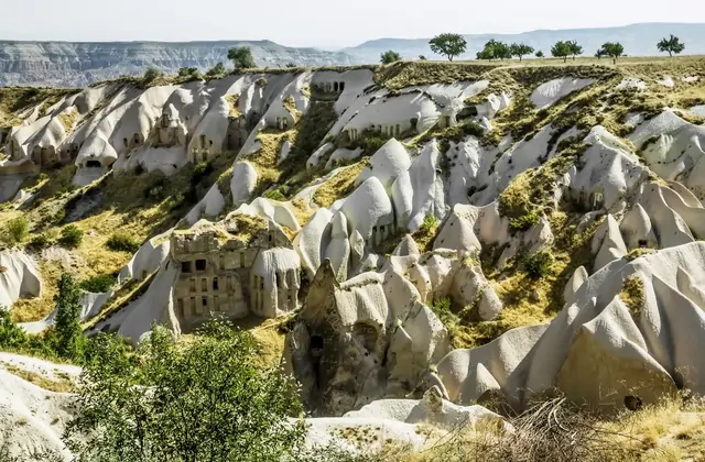 Le tonalità rosa-rosate delle formazioni di tufo erose che brillano nella luce del pomeriggio nella Valle dei Piccioni durante il Green Tour della Cappadocia. La calda tavolozza vulcanica della Cappadocia, Turchia, cambia meravigliosamente nel corso della giornata dall'alba al tramonto.