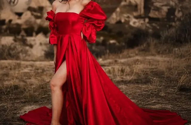 Una mujer con los brazos levantados en una alegre pose de moda durante una sesión de fotos en Capadocia, Turquía, irradiando la libertad y la maravilla de la fotografía de viaje en un recorrido turístico local.