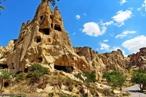 Visitantes explorando el complejo al aire libre del Museo de Göreme, con formaciones rocosas de chimeneas de hadas elevándose al fondo en Capadocia.