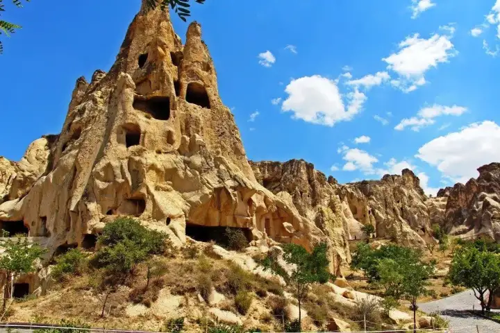 Visitatori che esplorano il complesso all'aperto del Museo di Göreme, con formazioni rocciose a camino delle fate che si innalzano sullo sfondo in Cappadocia.