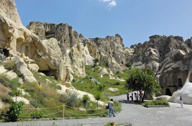 La luce del sole illumina la facciata tufacea di un monastero rupestre di Göreme nel Red Tour della Cappadocia, mostrando secoli di erosione naturale e intaglio umano.