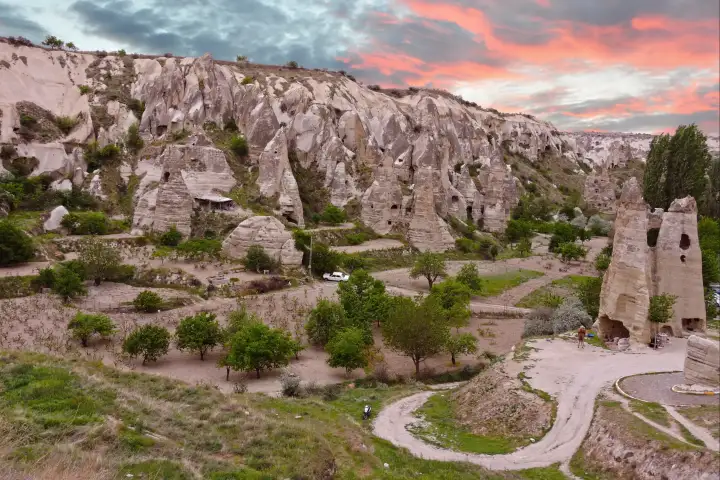 Luz de la mañana sobre el paisaje volcánico que rodea el Museo al Aire Libre de Göreme en Capadocia, con siluetas de globos aerostáticos flotando encima.