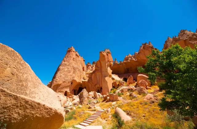 Un gruppo di turisti del Red Tour che camminano sul sentiero polveroso attraverso la Valle di Devrent, Cappadocia, circondati da formazioni di tufo vulcanico scolpite dal vento.