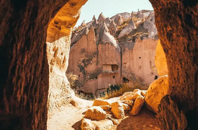 Fiori selvatici primaverili in fiore alla base delle scogliere di tufo nella Valle di Zelve, aggiungendo colori stagionali all'antico paesaggio roccioso nel Red Tour della Cappadocia.