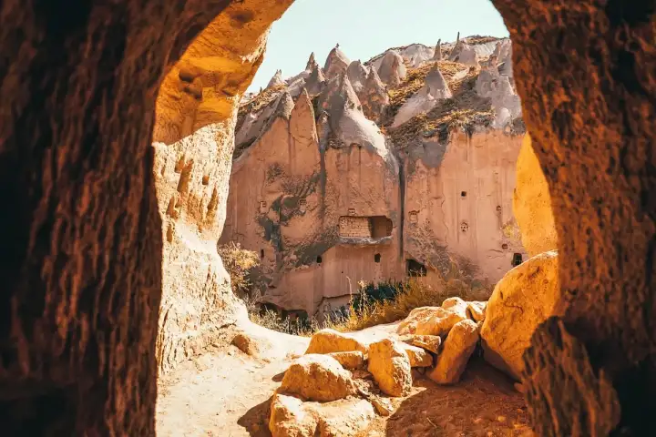 Fiori selvatici primaverili in fiore alla base delle scogliere di tufo nella Valle di Zelve, aggiungendo colori stagionali all'antico paesaggio roccioso nel Red Tour della Cappadocia.
