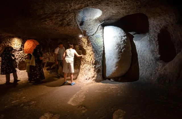 Narrow corridor between chambers in Özkonak Underground City, Cappadocia, illuminated by modern lighting to allow Yellow Tour visitors to safely navigate the ancient passages.