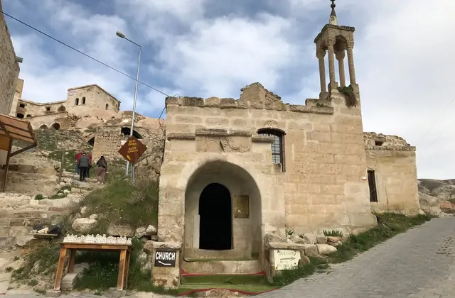 Multi-storey cave dwellings carved into the Çavuşin cliff face in Cappadocia, accessible via steep stone staircases explored on the Yellow Tour walk.