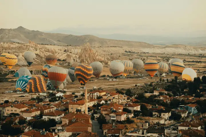 Ground crews prepare a colorful hot air balloon for launch near the stone houses of a traditional Cappadocian village, Turkey, in the calm before the morning flights.