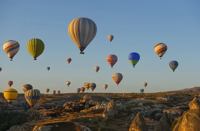 A balloon basket skims close above the tops of fairy chimneys in Cappadocia, Turkey, giving passengers an extraordinary low-altitude view of the cone-shaped volcanic rock landscape.