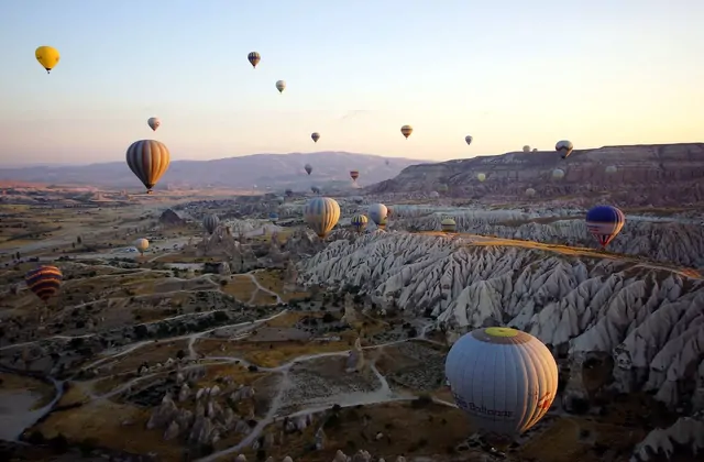 Desde una canasta de globo en vuelo, las puntas de las chimeneas de hadas de Capadocia aparecen justo debajo mientras otros globos flotan en el cálido aire matinal, Turquía, una vista solo disponible desde el aire.