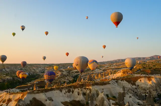 Durante l'ora d'oro, un volo in mongolfiera sulle valli erose della Cappadocia, Turchia, diventa uno studio di luce: il sole basso dipinge le pareti del canyon in toni di rame fuso.