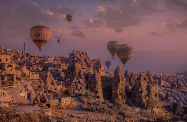 Las casas cueva de Göreme, Capadocia, Turquía, emergen de la suave luz anterior al amanecer mientras los primeros globos aerostáticos de la mañana inician su ascenso sobre los tejados de piedra tallada.