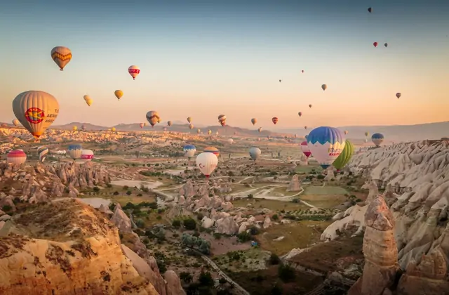 Dozens of hot air balloons fill every corner of the morning sky above the wide open valleys of Cappadocia, Turkey, creating the region's most iconic spectacle of color and flight.