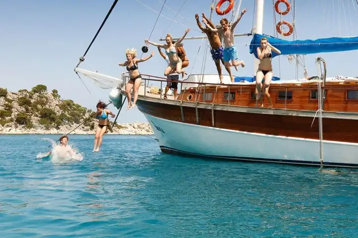 Fethiye's natural harbor contains a forest of sailboat masts bobbing in crystalline waters, with dramatic Lycian cliffs and pine forests providing a theatrical Mediterranean backdrop.