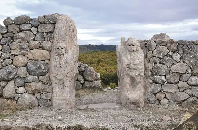 La Porta del Re a Hattusa, la capitale ittita Patrimonio dell'Umanità UNESCO vicino a Boğazkale, Turchia, incornicia un paesaggio autunnale attraverso la sua apertura, con le due sfingi guardiane in calcare scolpito che si fronteggiano attraverso l'antico soglio.