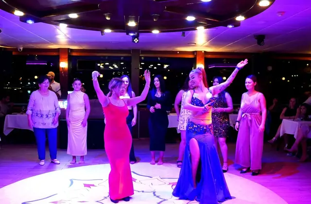 Una danzatrice del ventre solista in costume luccicante in primo piano sul palco durante una crociera serale sul Bosforo a Istanbul, momento clou dello spettacolo di cena turca tradizionale.