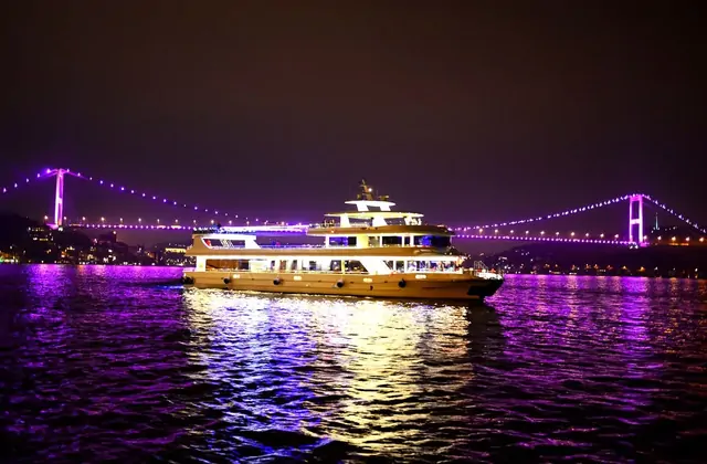 Un battello da cena in crociera sul Bosforo di Istanbul che passa sotto un illuminato ponte del Bosforo di notte, catturando il drammatico momento turistico di navigare sotto uno degli iconici ponti sospesi di Istanbul.