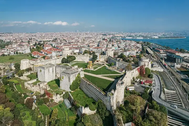 Una fotografia aerea dall'alto delle antiche mura maritime bizantine di Istanbul mostra il complesso della fortezza direttamente dall'alto, con le sue massicce torri, le cortine difensive interna ed esterna e il recinto verde interno chiaramente visibili, il Bosforo e il denso tessuto urbano di Ista