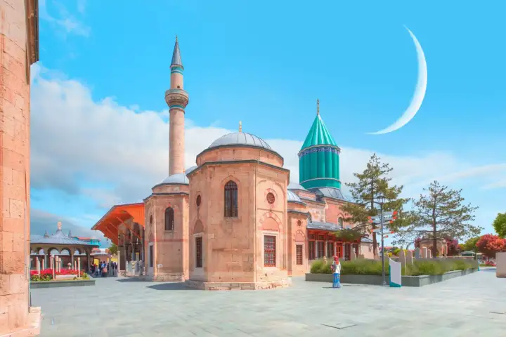 Una vibrante escena diurna en la plaza abierta del Museo Mevlana en Konya, con un alto minarete y la cúpula cónica turquesa de la tumba de Rumi elevándose detrás de un edificio de mezquita octagonal de piedra, con una gran luna creciente visible en el cielo azul brillante.