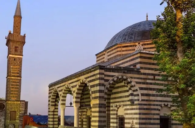 Il minarete a fasce della Moschea Kasım Padişah a Diyarbakır mostra le sue caratteristiche bande alternate di basalto nero e calcare chiaro contro un cielo sereno, uno dei dettagli architettonici più fotogenici della storica città vecchia.