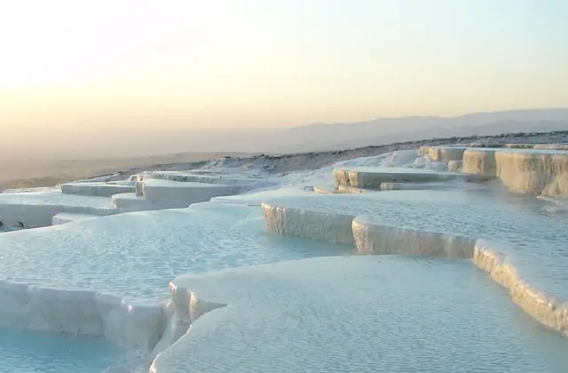 Vista grandangolare delle terrazze di travertino del Castello di Cotone di Pamukkale nel tardo pomeriggio a Denizli, Turchia, livelli rettangolari piatti di acqua calcarea poco profonda che si estendono verso l'orizzonte.