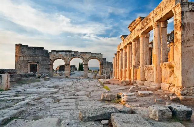 La calle porticada Frontino en la antigua Hierápolis cerca de Pamukkale, Turquía, cálida luz dorada golpeando el lado derecho de la avenida al anochecer, las bien conservadas columnas romanas proyectando largas sombras.