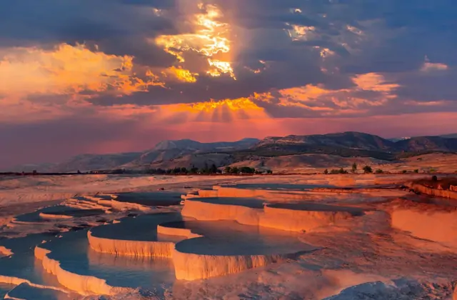 Il teatro di Hierapolis a Pamukkale, Turchia ripreso di lato, che mostra le sedute in pietra curve che riempiono l'inquadratura con la ricca facciata della casa del palcoscenico romano al centro destra.